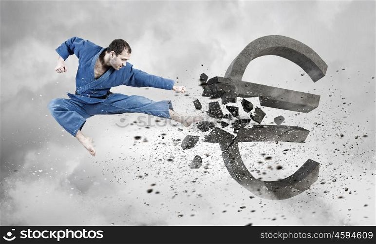 Karate man attack euro. Young determined karate man breaking with leg concrete euro sign