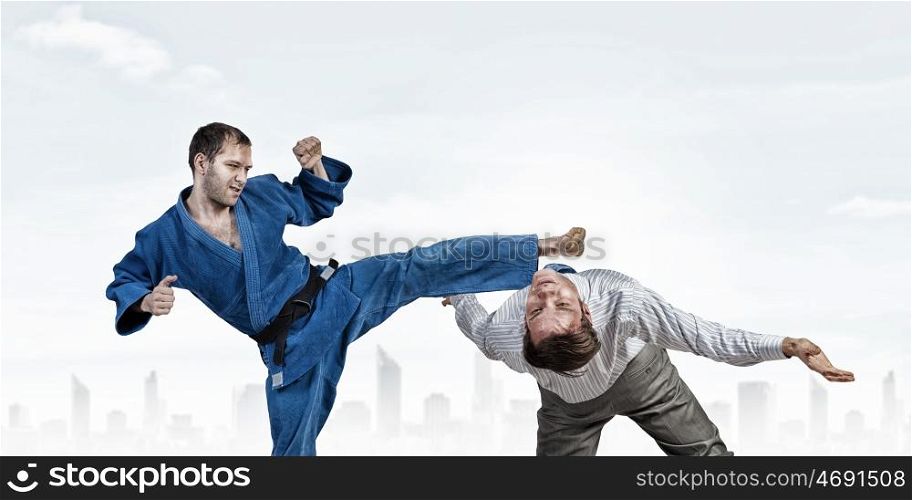 Karate man in blue kimino. Young determined karate man fighting with businessman in suit