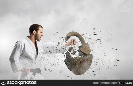 Karate man in white kimino. Young determined karate man breaking with anger concrete lock