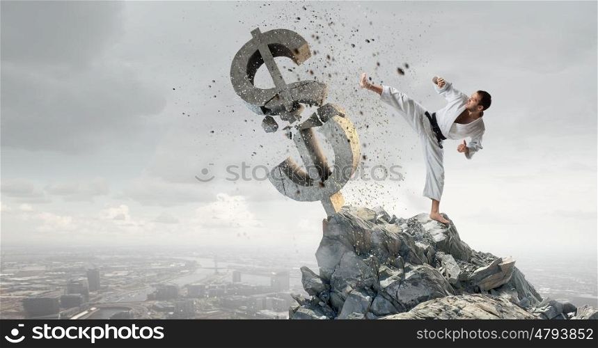 Karate man in white kimino. Young determined karate man breaking with leg concrete dollar sign