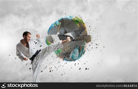 Karate man in white kimino. Young determined karate man breaking with leg concrete Earth planet. Elements of this image are furnished by NASA