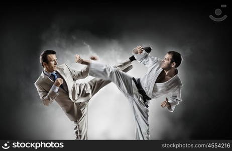 Karate man in white kimino. Young determined karate man fighting with businessman in suit