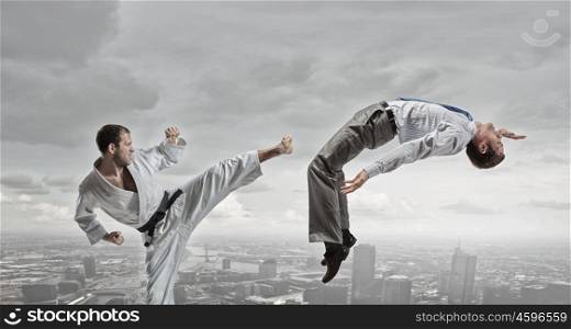 Karate man in white kimino. Young determined karate man fighting with businessman in suit