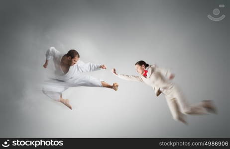 Karate man in white kimino. Young determined karate man fighting with businesswoman in suit