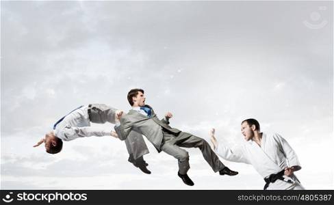 Karate man in white kimino. Young determined karate man fighting with team of businesspeople