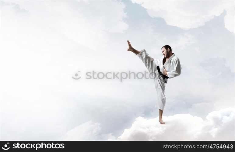 Karate man in white kimino. Young determined karate man on cloud high in sky