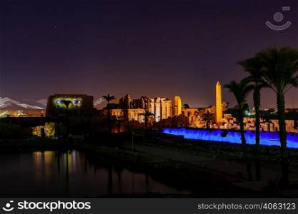 Karnak Temple Complex in the night with a high obelisk and sacred lake, Luxor, Upper Egypt.