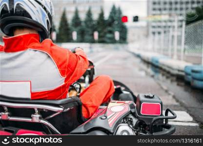 Karting racer, go kart driver in helmet, back view. Carting speed track