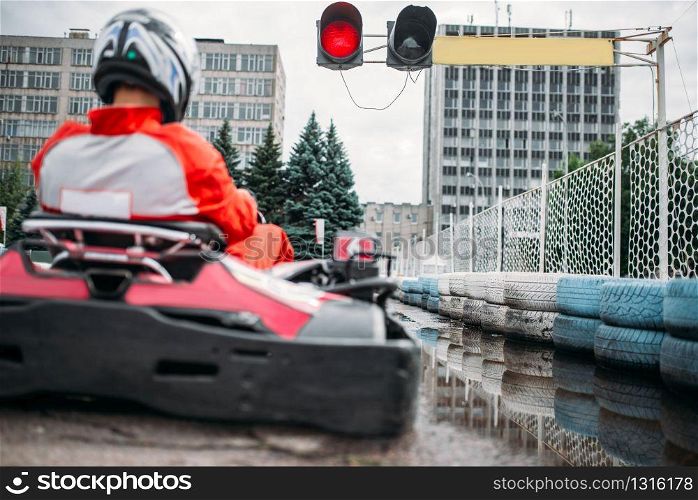 Karting racer, go kart driver on start line, back view. Carting speed trac, extreme motor sport