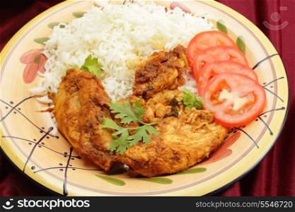 Kashmiri chicken - marinaded with spices and tomato sauce and fried with garlic and ginger - on a plate with boiled white basmati rice