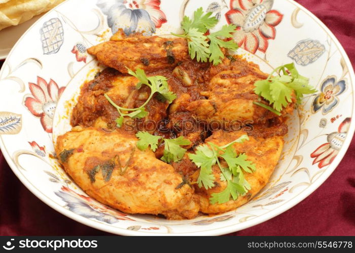 Kashmiri chicken - marinaded with spices and tomato sauce and fried with garlic and ginger -in a serving bowl