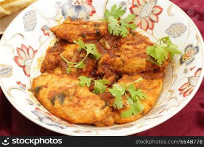 Kashmiri chicken - marinaded with spices and tomato sauce and fried with garlic and ginger -in a serving bowl