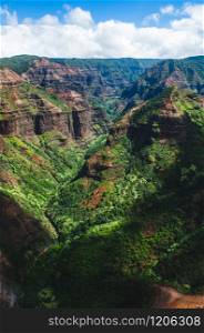 Kauai is Hawaii&rsquo;s fourth largest island and is sometimes called the Garden Island, which is an entirely accurate description. Beautiful dark green canyon, mountain range and cloudy sky in Kauai, US