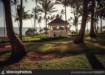 Kauai is Hawaii&rsquo;s fourth largest island and is sometimes called the Garden Island, which is an entirely accurate description. Wooden pavilion, palm trees, the sea and almost sunset in Kauai, US