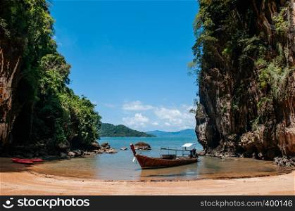 Kayak and Thai wooden longtail boat on the beach at sea cliff of Koh Talabeng near Koh Lanta, Krabi, Thailand