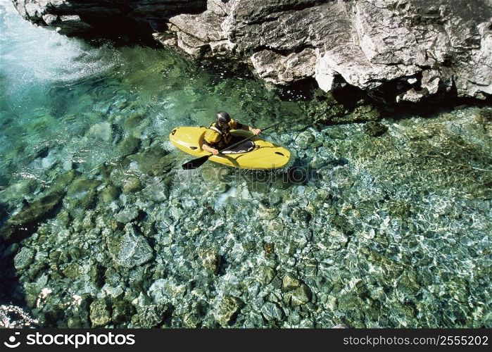 Kayaker in calm water near large rocks