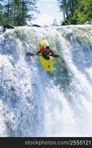 Kayaker in rapids coming over waterfall (selective focus)