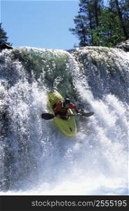 Kayaker in rapids going over waterfall