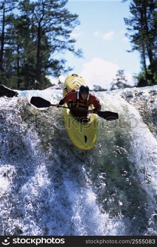 Kayaker in rapids going over waterfall (selective focus)