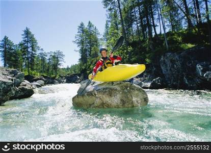 Kayaker on top of rock in rapids smiling