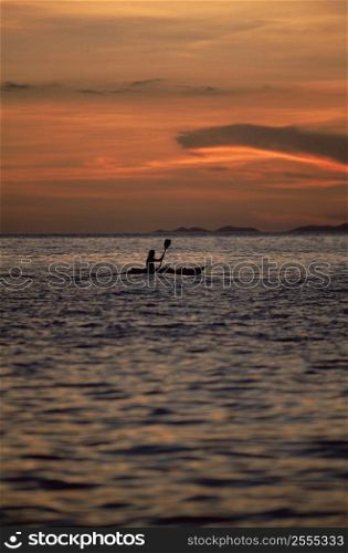 Kayaker outdoors in ocean at sunset (far away/silhouette)