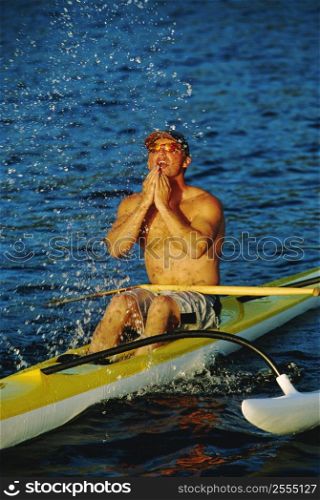 Kayakers sitting in kayak and splashing water on face (selective focus)