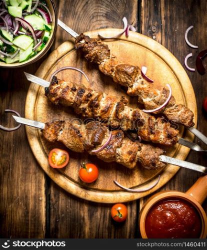 Kebab with fresh salad of cucumbers and onions. On wooden background.. Kebab with fresh salad of cucumbers and onions.