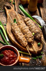 Kebab with tomato sauce and spices. On a wooden table.. Kebab with tomato sauce and spices.
