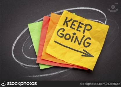 keep going - motivation or determination concept - handwriting on colorful sticky notes against black paper