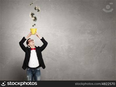 Keep your investments safe. Young businessman holding bucket with currency signs flying out