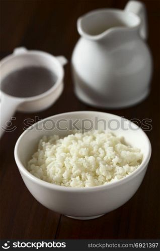 Kefir grains in bowl, strainer and milk in the back, photographed with natural light (Selective Focus, Focus one third into the kefir grains). Kefir Grains