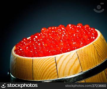 Keg of red caviar on the dark