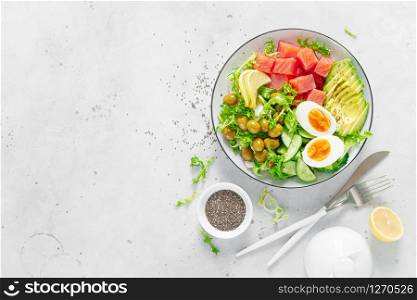 Ketogenic, keto or paleo diet lunch bowl with salted salmon fish, lemon, avocado, olives, boiled egg, cucumber, green lettuce salad and chia seeds. Healthy food trend. Top view