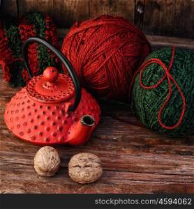 Kettle and knitting. Stylish teapot with warm tea and balls of wool to knit