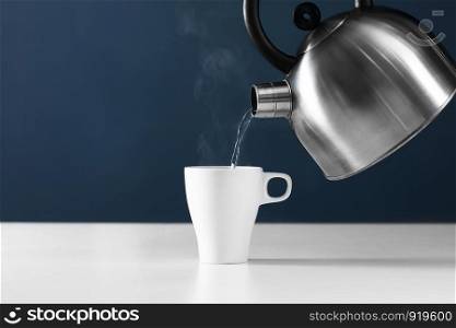 kettle pouring boiling water into a cup with smoke on wood table. retro kettle pouring water into a cup on a white background with smoke on wood table