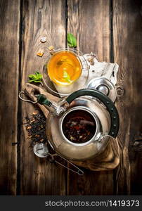 Kettle with fragrant floral tea. On wooden background.. Kettle with fragrant floral tea.