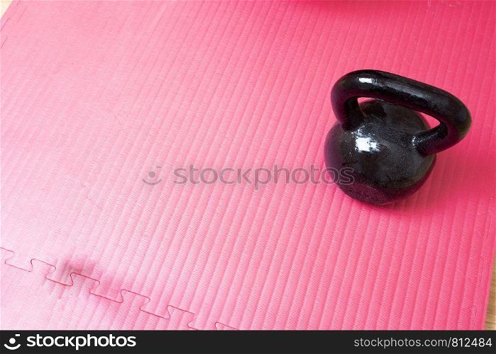 Kettlebell and pink yoga mat on the floor, sport concept space for text. healthy lifestyle. Kettlebell and pink yoga mat on the floor, sport concept space for text