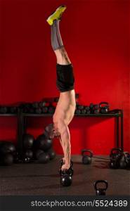 kettlebell handstand man workout in red gym with dumbbells background