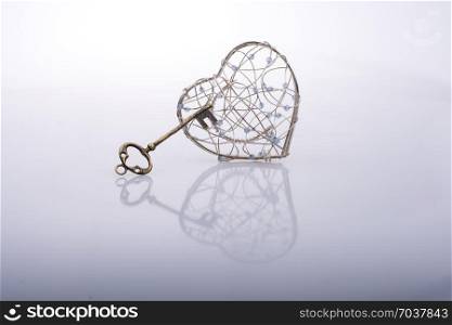Key and a heart shaped metal cage on white
