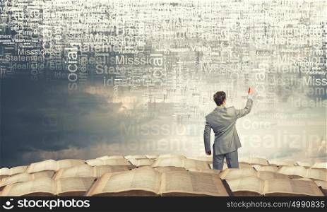 Key concepts to your success. Back view of businessman writing leadership concepts on wall