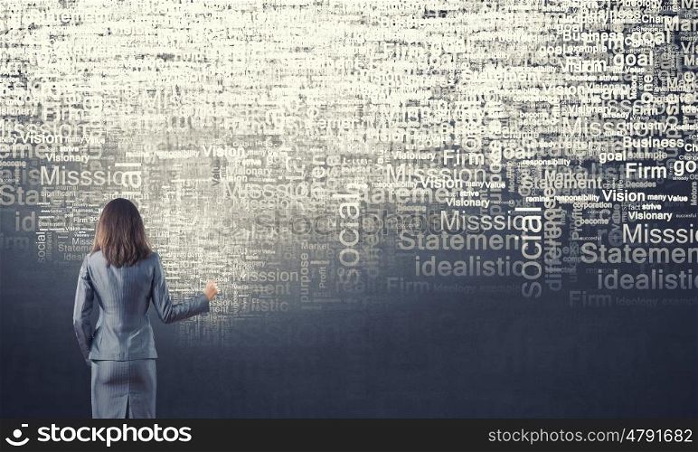 Key concepts to your success. Back view of businesswoman writing leadership concepts on wall