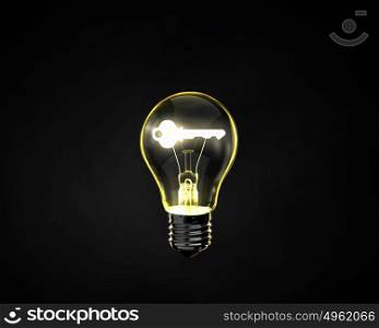 Key idea. Light bulb with key inside on dark background