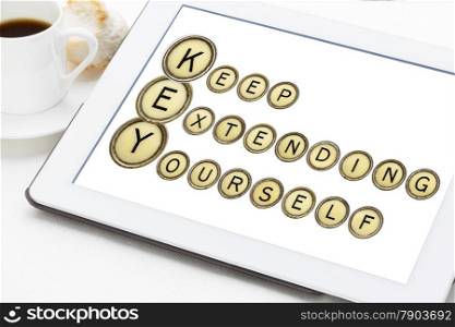 KEY - keep extending yourself - motivation acronym explained in isolated vintage typewriter keys on a digital tablet with a cup of coffee
