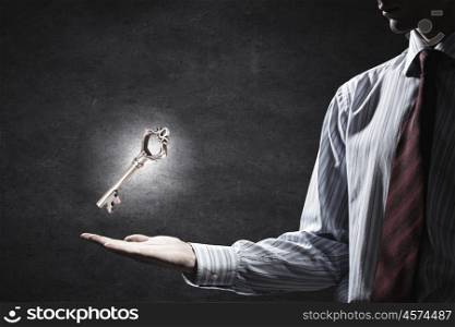 Key symbol in hand. Close up of businessman hand showing key to success
