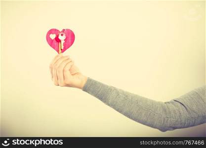 Key to happiness and living together. Love and dream. Woman hand holds little red heart with keys to new home house flat apartment. . Female hand holds little heart with keys.