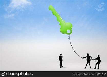 Key to success. Silhouettes of business people pulling key with rope