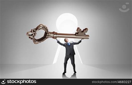 Key to success. Young businessman and lifting big key above head
