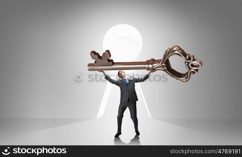 Key to success. Young businessman and lifting big key above head