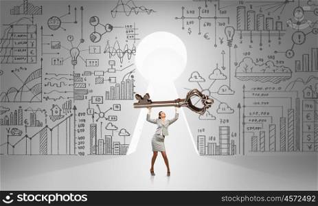 Key to success. Young businesswoman and keyhole at background lifting big key above head