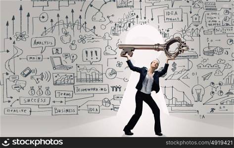Key to success. Young businesswoman and keyhole at background lifting big key above head